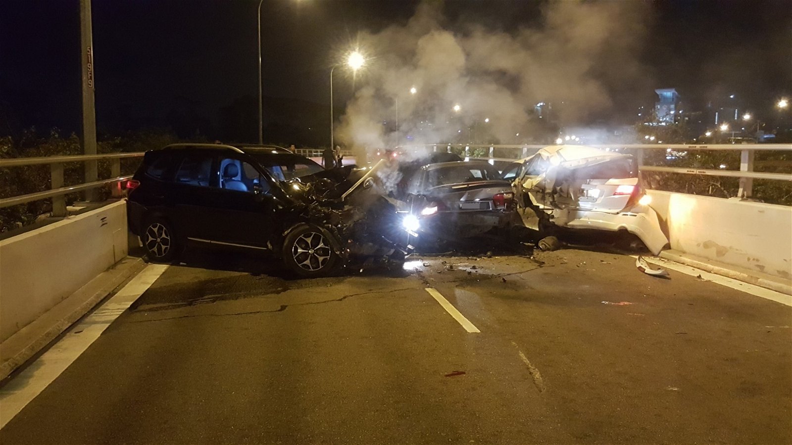 4辆轿车被撞得扭曲变形，其中车头毁损情况严重的黑色轿 车，更不断冒烟。事故也造成两名司机受伤送院治疗。