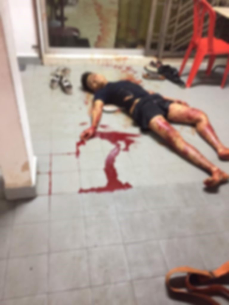 来自新加坡的伤者被砍伤后，血迹斑斑躺在地上等待救援。