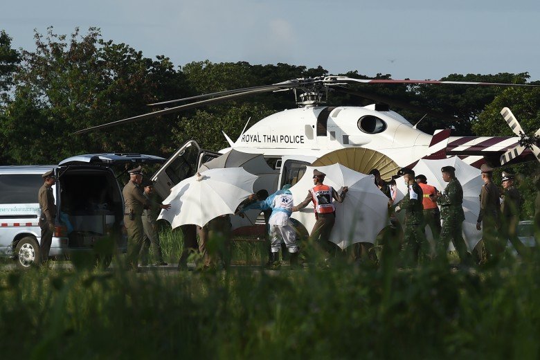 救援人员以伞掩护，据悉是抬担架送第5名获救少年上救护车。