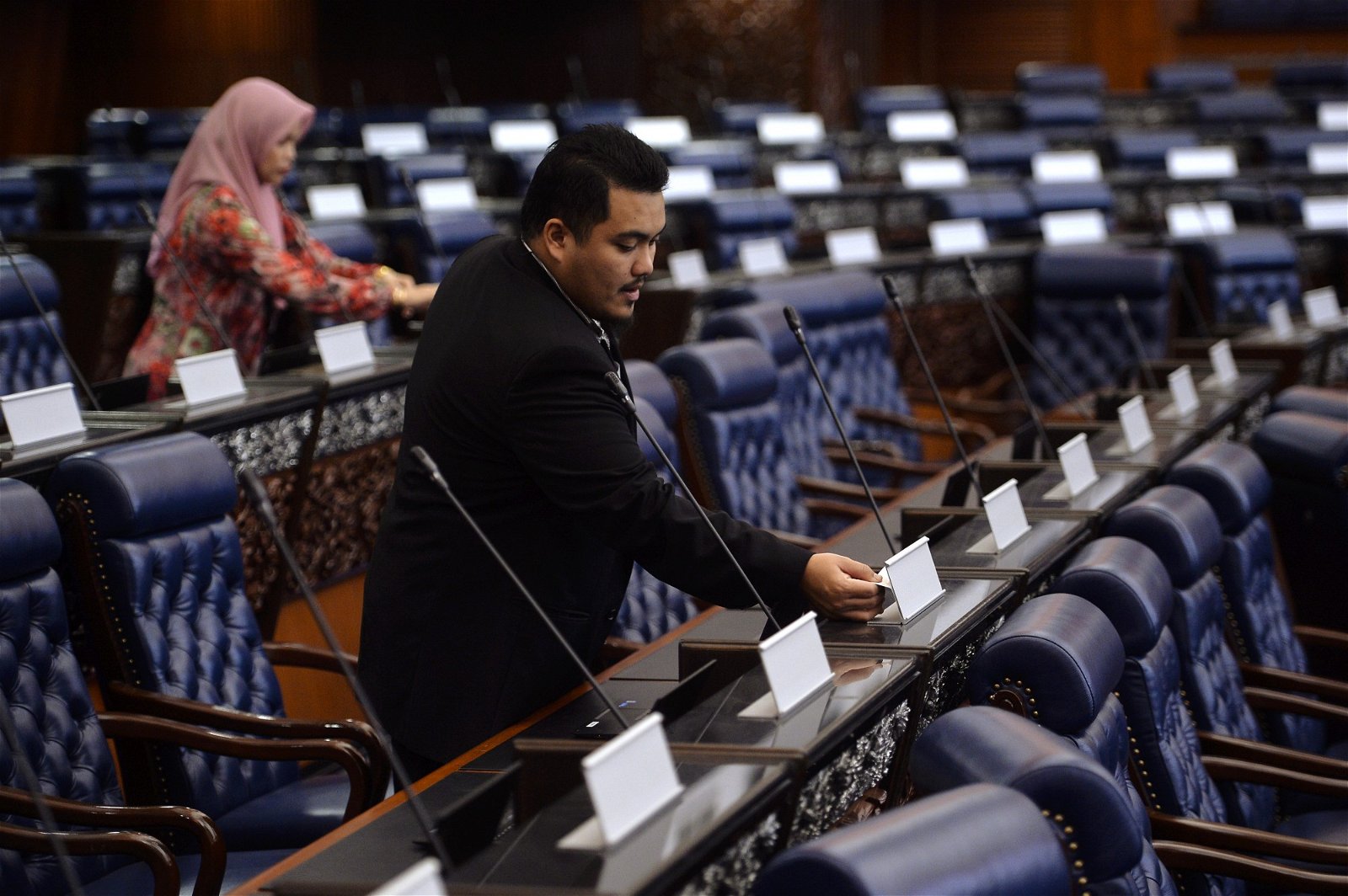 国会下议院内，数名国会大厦的职员在检查国会议员座位上的名牌，以 便在下周二复会时万无一失。