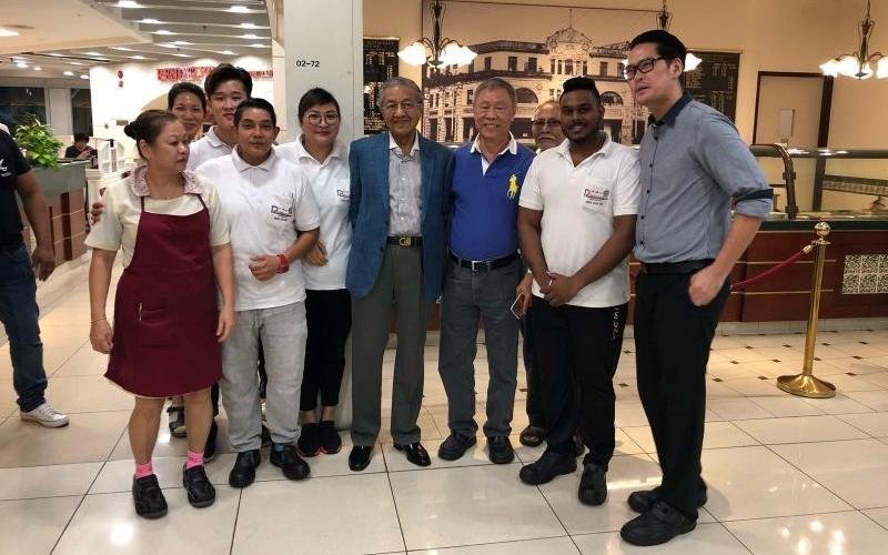 马哈迪（前排左4）前天傍晚约6时到福乐居餐馆用餐，并与餐馆老板谢琼明（左5）以及侍应生合影。（照片取自联合早报网）