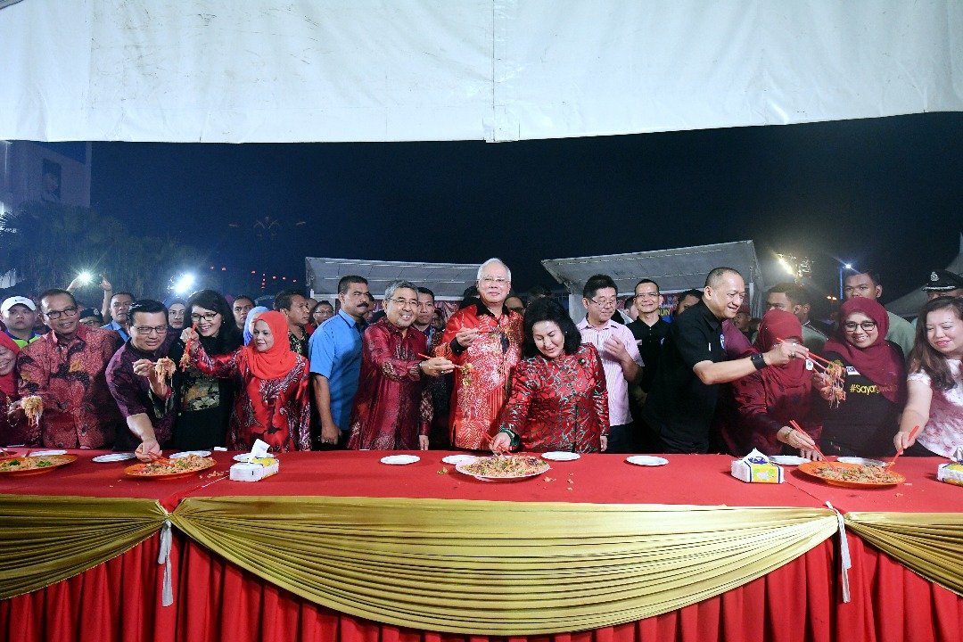 全国华人新年大团拜众嘉宾在捞生环节时，把食材高高捞起，寓意来年风生水起。左7起首相伉俪；左2廖中莱及右4纳兹里。