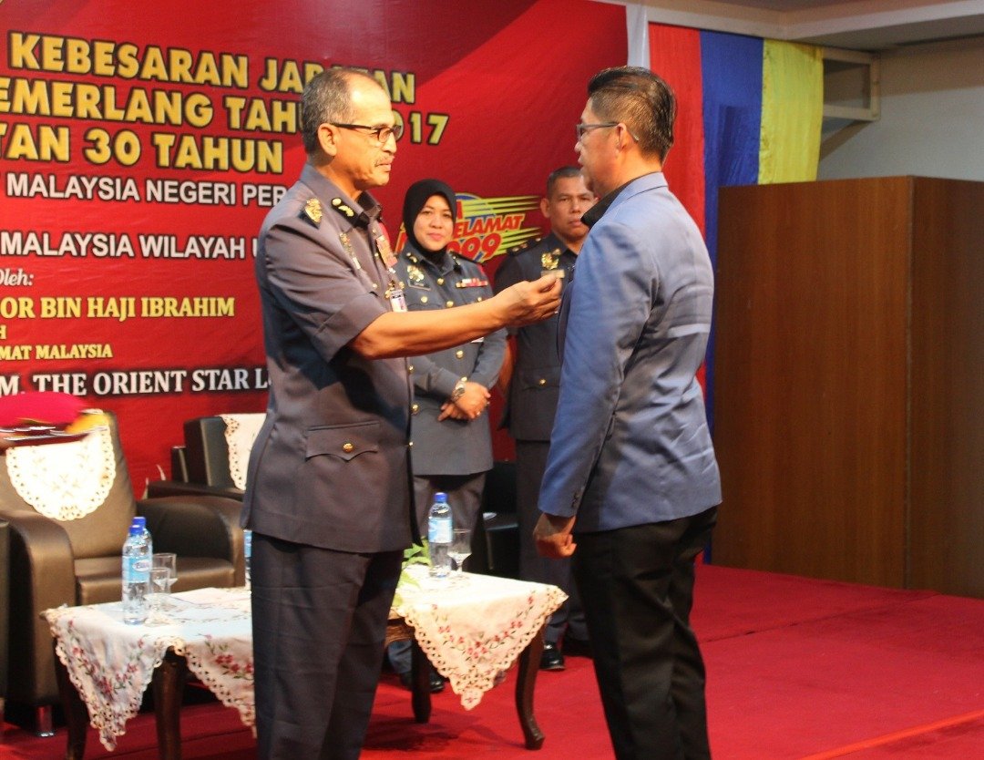 旺莫哈末诺（左）颁发荣誉勋章予其中一名获褒扬的志愿消拯队员。