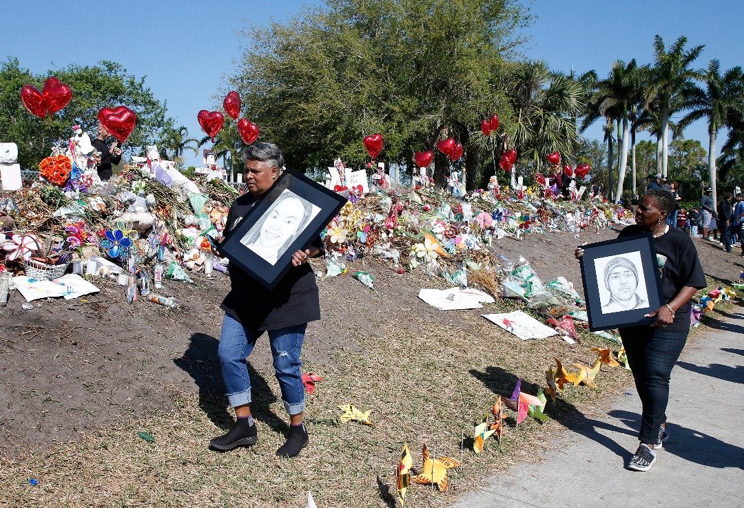 在发生枪击惨案的佛州帕克兰市道格拉斯高中，有民众于周三手持两名遇害者的素描经过为枪击案17名遇害者所设的临时纪念处。
