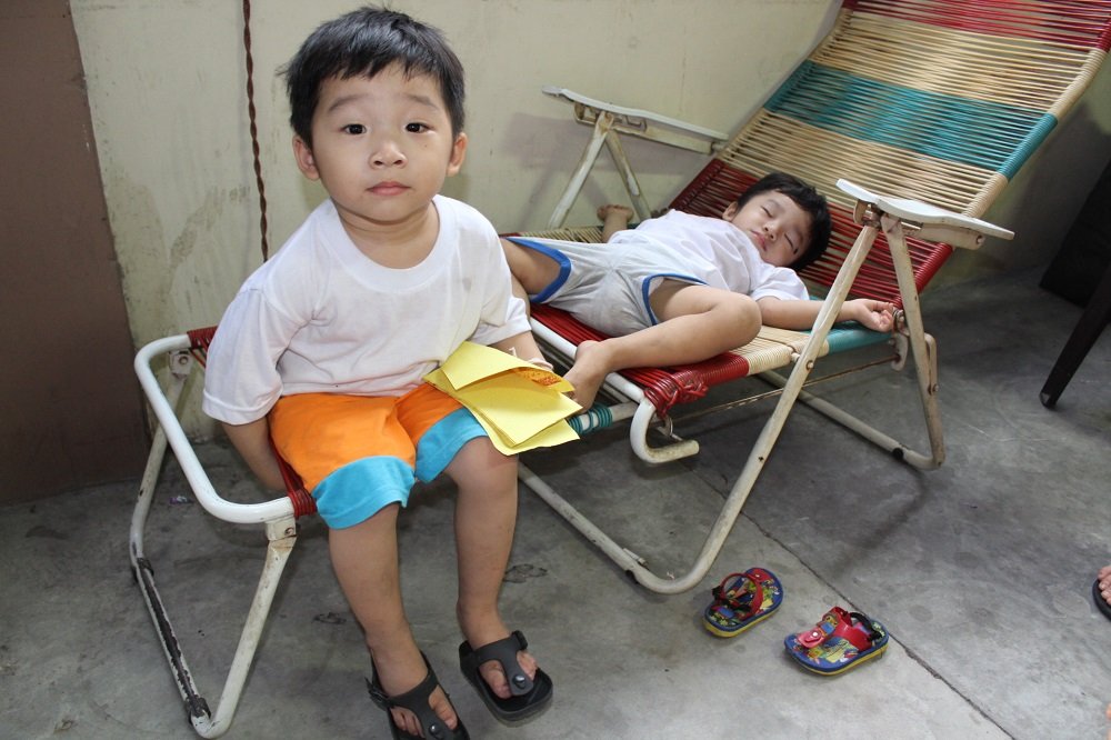 面对爸爸的骤逝，大儿子黄伟康（左）似乎懵懵懂懂，小儿子黄伟权（右）因过于疲惫而睡在善堂的椅子上。