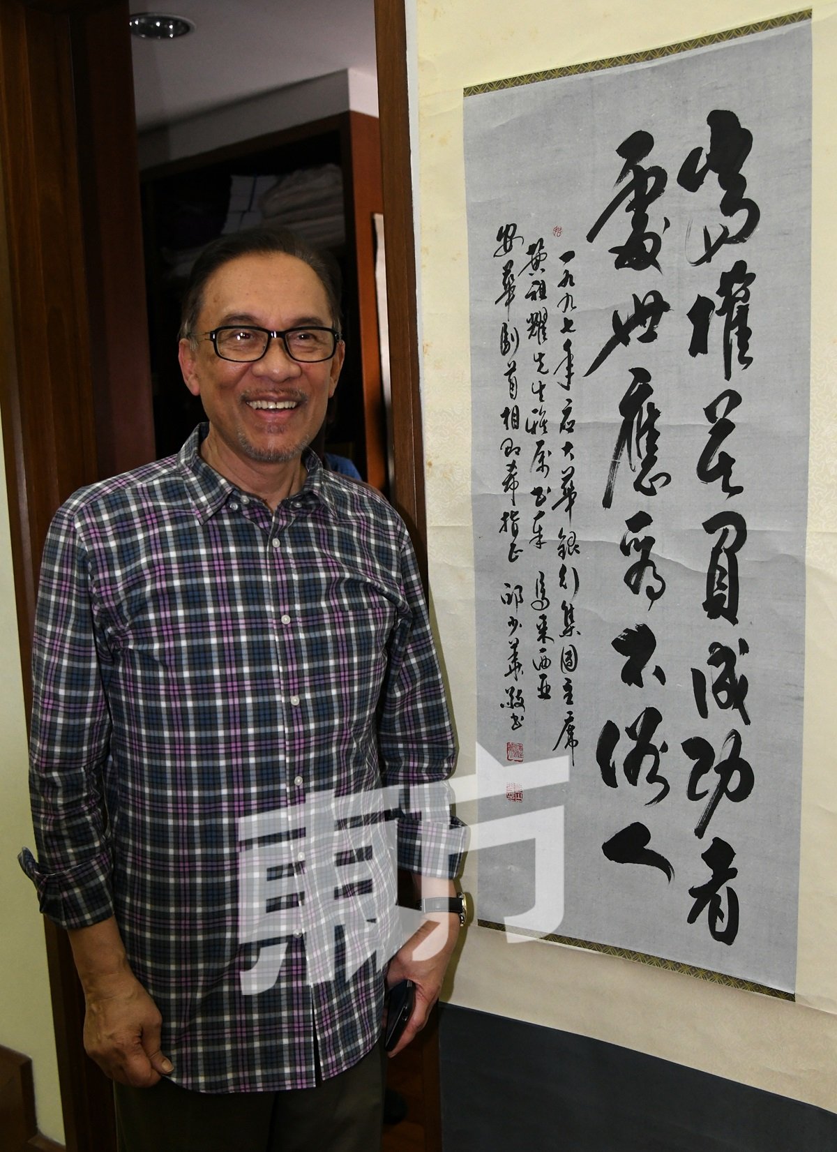 安华接受中文媒体联访，特在家中会客厅悬挂的墨宝傍合照。