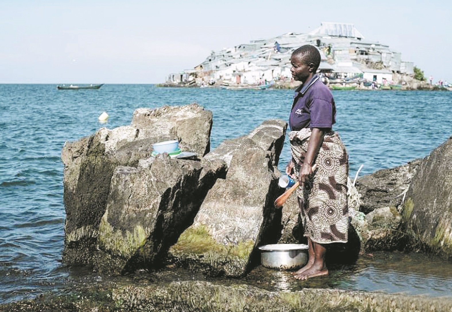 米金戈岛附近岛屿上的一名妇女，在岸边洗盘子和杯子。不远处的米金戈岛，周围的鱼类丰富，主要盛产尼罗河鲈鱼和罗非鱼。这些非洲渔民为了获得那里极其丰富的鱼类，才拼命往岛上挤。