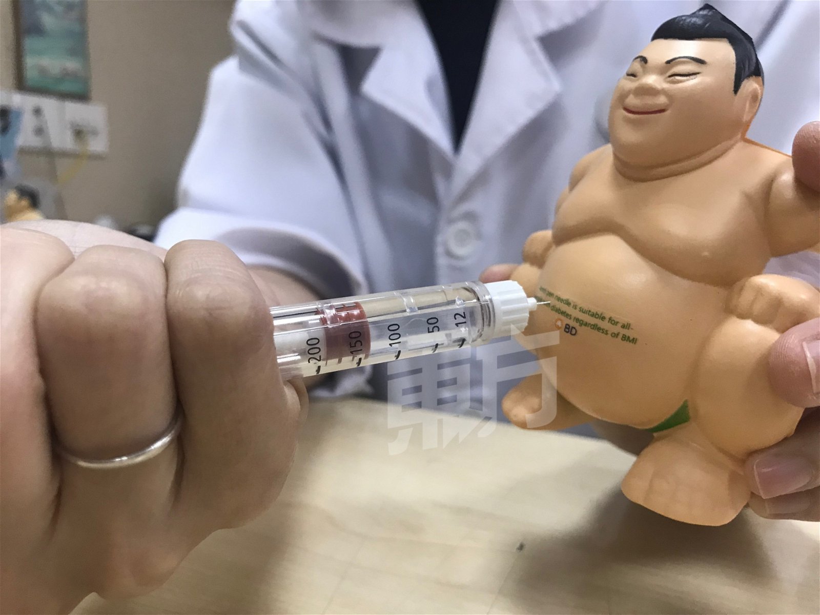 护理师用模型示范如何注射胰岛素。对准腹部再插入针，等待10至15秒再拔出。