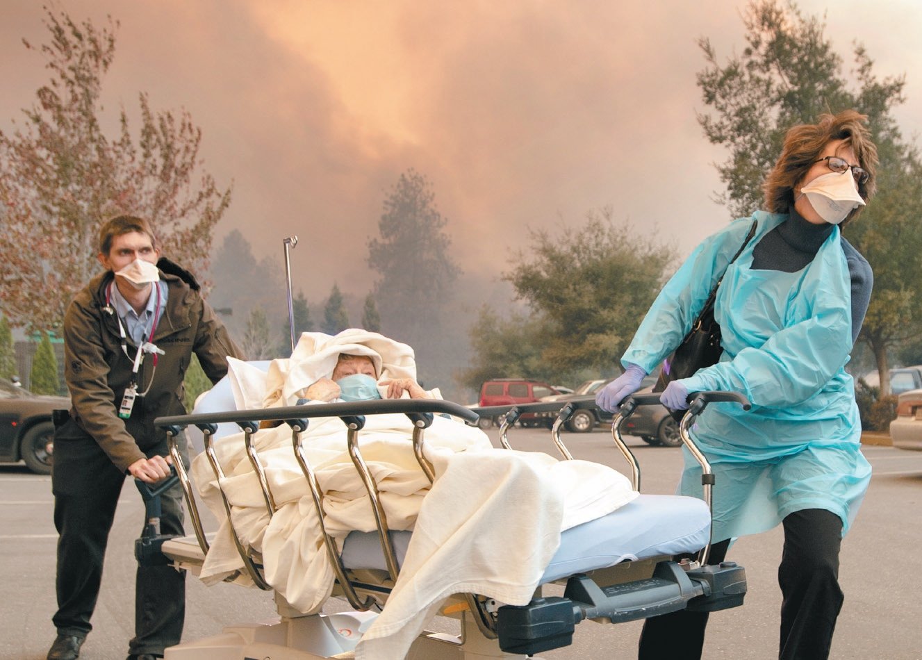 山林大火迅速逼近，天堂镇的一家医院进行紧急疏散，医护人员加 快脚步将病患送往他处避难。