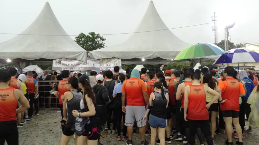 0公里路跑项目临时取消了，参赛者冒著雨到终点帐篷排队领取奖牌。