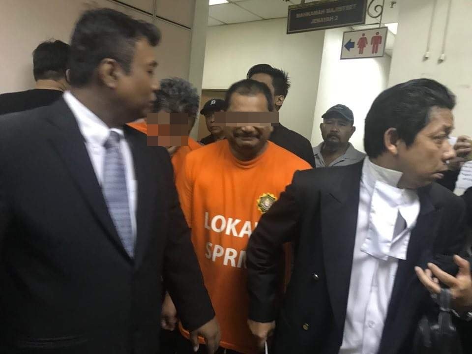 罗海兹（左2）被反贪会官员押往新山法庭时，全程淡定微笑面对媒体镜头。