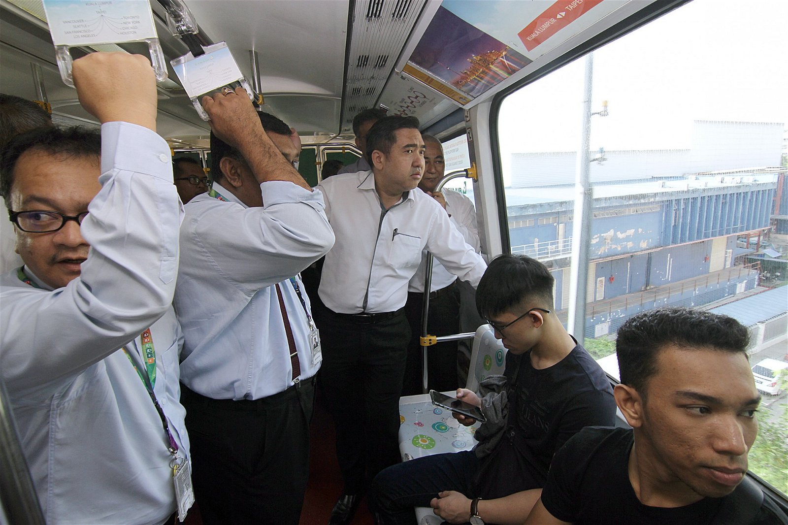 陆兆福（中）继巡视轻快铁服务后，周二搭乘单轨火车，亲自体验服务。