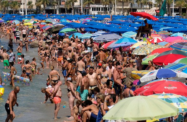 2018年夏季热浪袭欧洲，西班牙一度出现47度破纪录高温，沙滩上挤满了泡水消暑的民众。