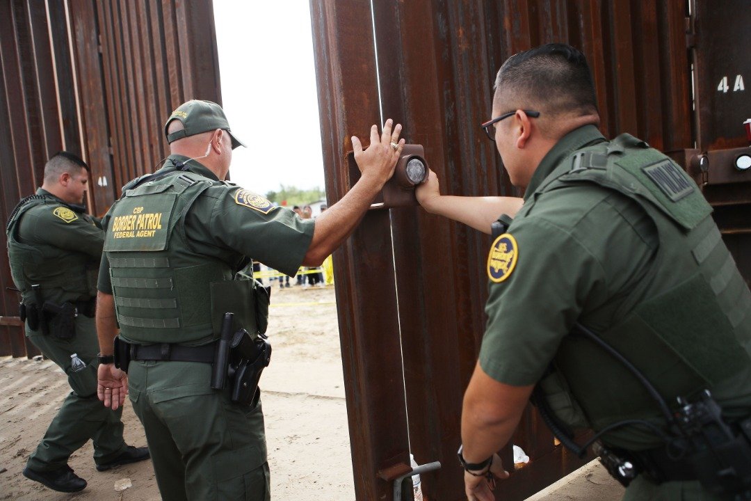 移民团聚活动在当天上午11时结束后，3名美国巡逻队队员关上了这道位于美墨边境的栅栏大门。
