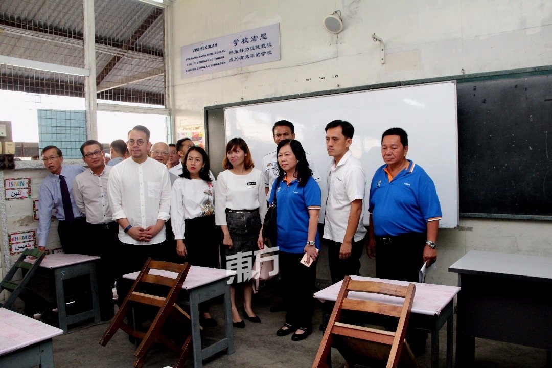 张念群（左5起）在峇东丁宜华小校长苏爱华等人陪同下，巡视该校的木板屋教室。左3为起为沈志强、王丽丽及吴俊益。