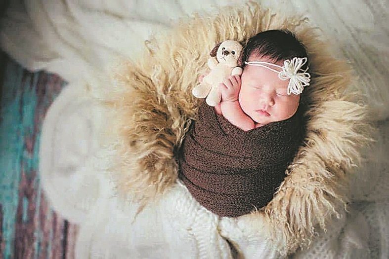 新生儿在拍摄时被布包裹著，仿如回到母亲的子宫，获得安全感后会沉沉入睡。