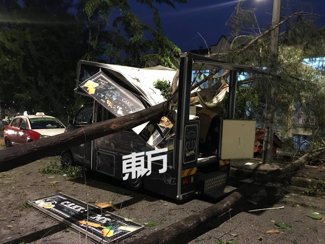 被强风刮倒的大树，压向停在路边的餐车，除了招牌被打落，厨房范围也毁不成形。