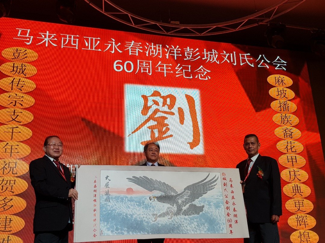 庆委会主席刘坤福（左）和刘同梓（右）一同接领中国福建永春湖洋彭城代表赠送的墨宝。