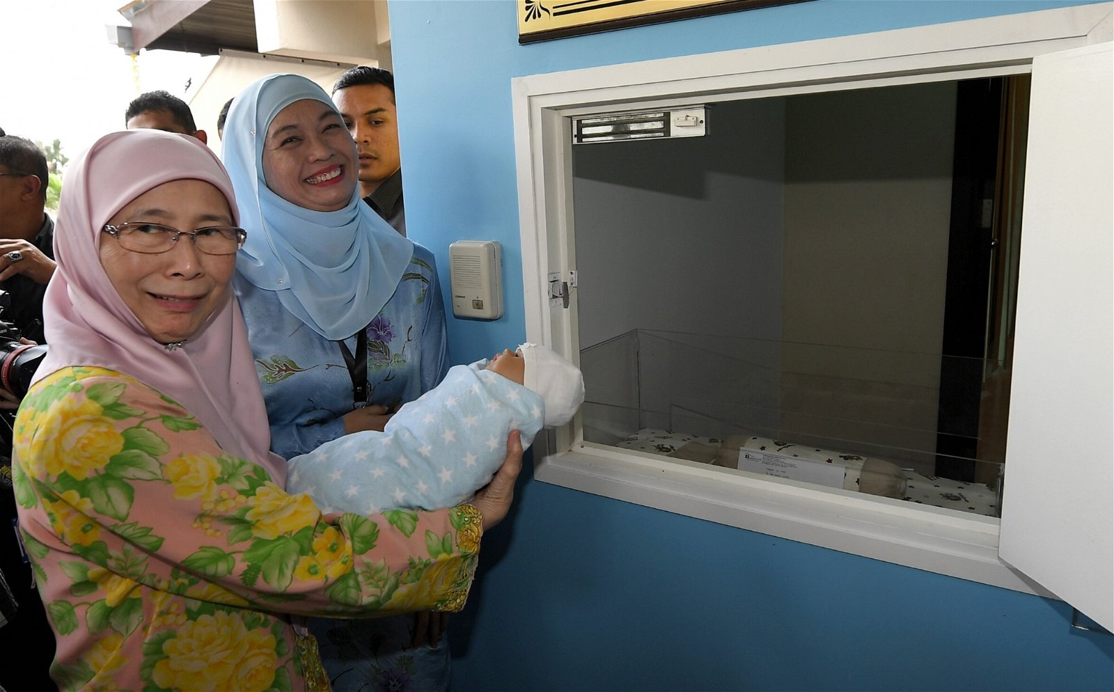 旺阿兹莎（左）拜访八打灵再也一家孤儿关怀保护中心后，向媒体记者展示如何将婴儿放入该中心的弃婴舱。