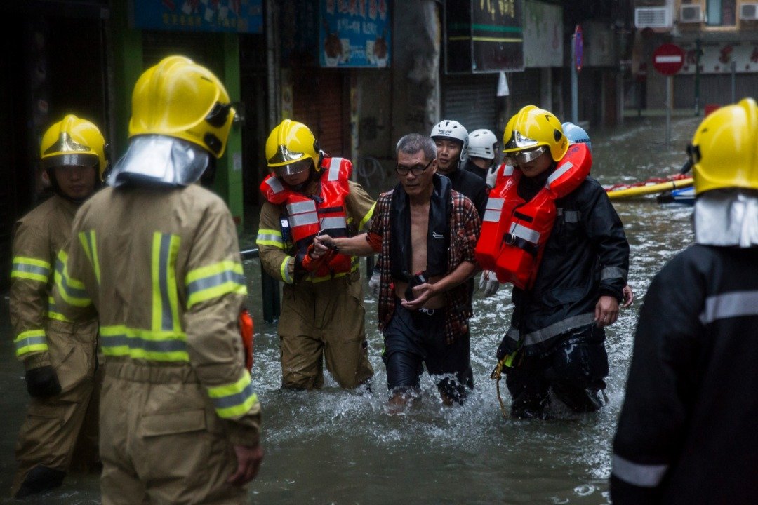 图说：“山竹”威力惊人，澳门多个地方淹水超过一公尺，消防人员救出一名受困店主（中）。-法新社-