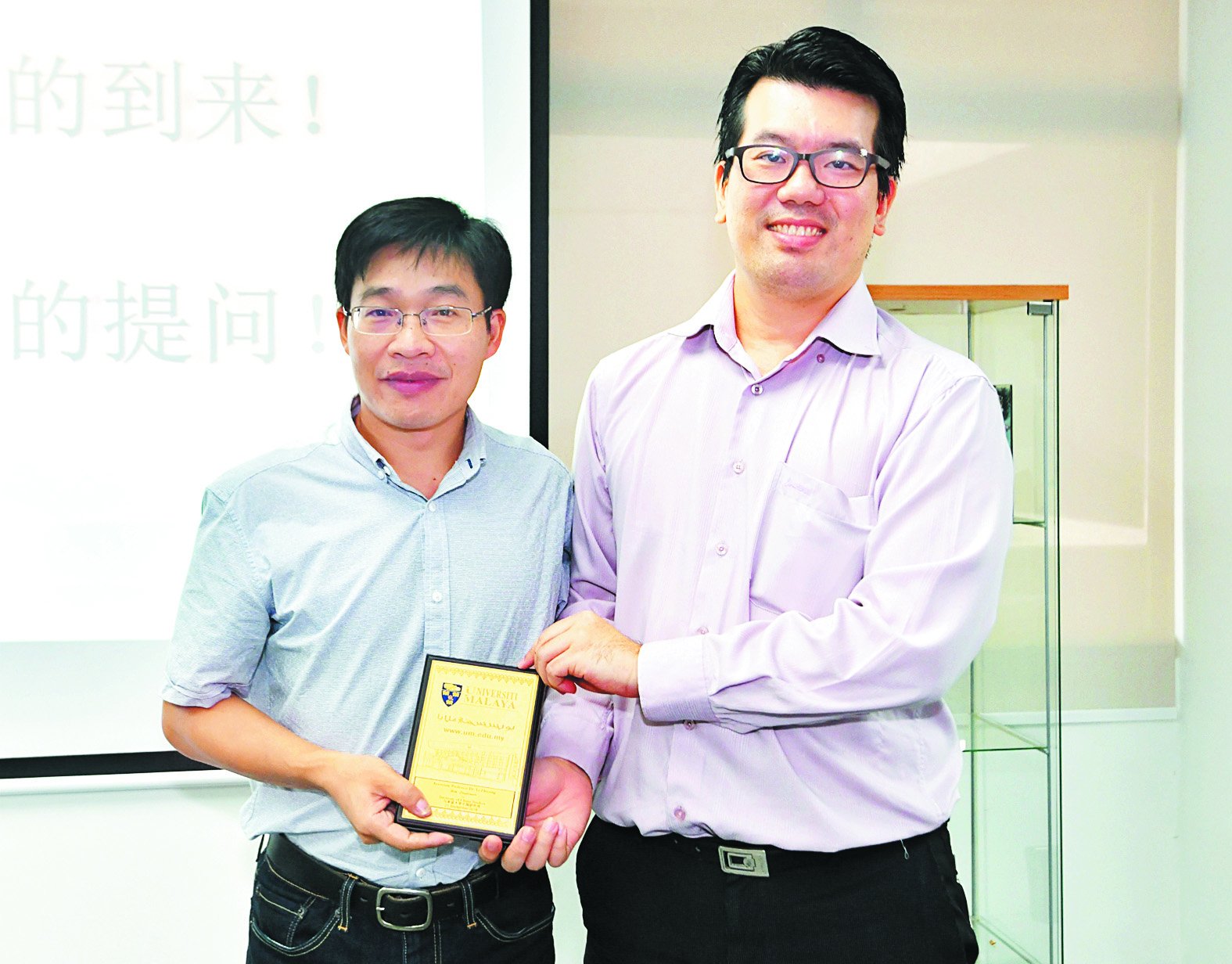 李志永（左）完成座谈会后，获得马大中国研究所副所长饶 兆斌赠送的纪念品。 （摄影：张真甄）