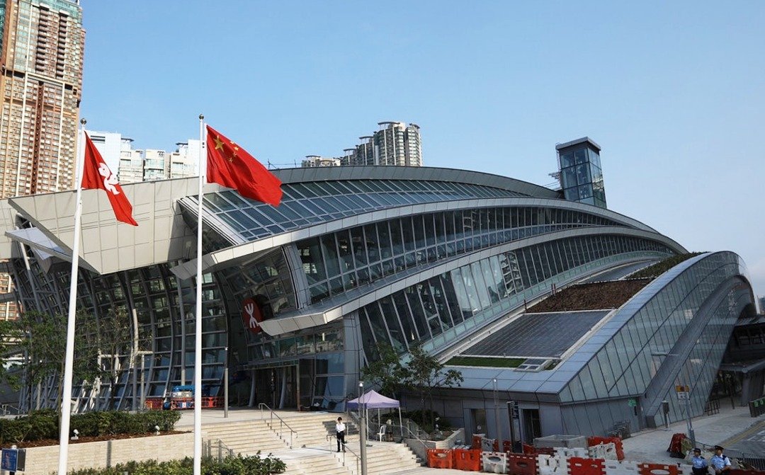广深港高铁西九龙站外的中国和香港旗帜飘扬。西九龙站主要设施设于地底，站内设4层地下楼层，分别为B1售票大堂、B2香港口岸区、B3内地口岸区，以及B4月台层。