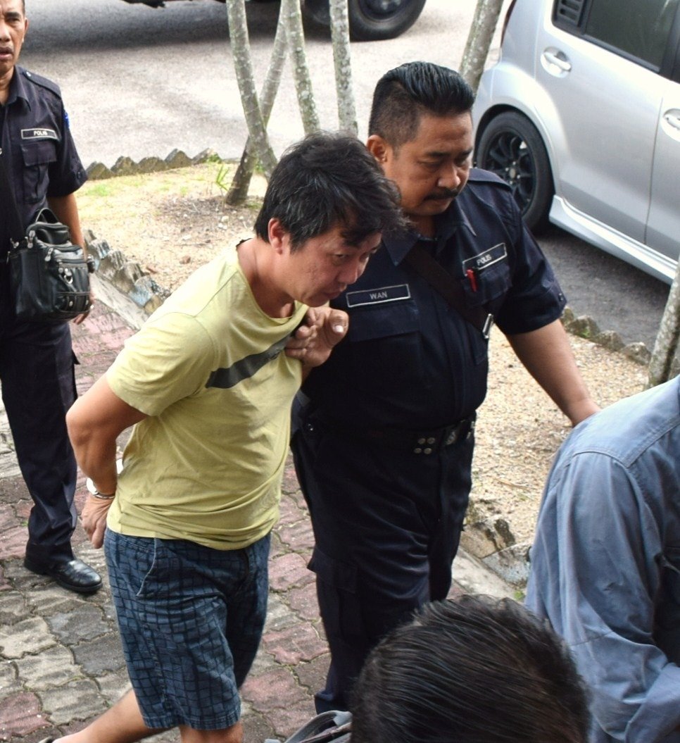 一身便服及双手上铐的被告（左），被带上法庭面对死刑的提控。