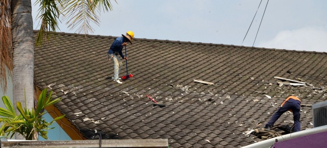工友在小礼堂屋顶上清理被狂风摧残的碎瓦片。