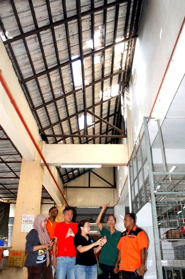 甘榜峇鲁巴刹屋顶上的瓦片被风灾摧残，多处破洞，王丽丽（左4）与官员等人协商修复工作。