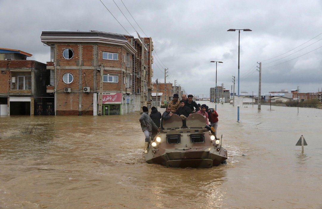 灾民们搭乘著伊朗军方的装甲车在水中行驶，并朝著安全的地方进发。洪灾发生后，伊朗当局随即出动了紧急直升机，并已疏散逾8万6000人。