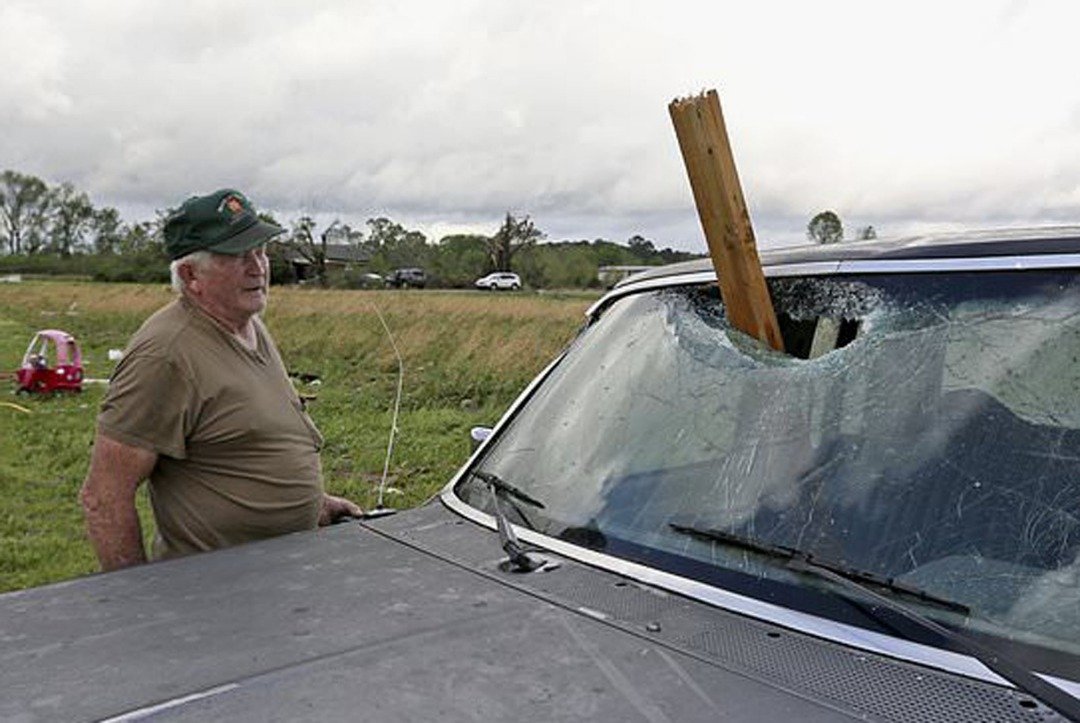 一名男子正一脸无奈地望著被风暴吹起并砸毁汽车挡风玻璃的木头。美国气象学家指出，“龙卷风警告”周日仍对阿拉巴马州东南部有效。
