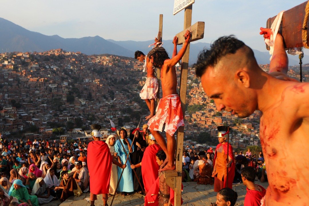 委内瑞拉首都加拉加斯的佩塔雷贫民窟，民众坐在空地上看著耶稣受难的表演。委内瑞拉是天主教国家，因政局动荡，委内瑞拉人正面对经济崩溃和人道危机，很多人选择离开寻找新生活；离不开的，或许可靠著信仰生活下去。