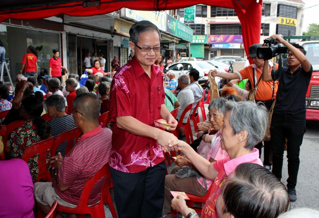 李文材（左）在选区活动上，分发红包予乐龄人士。