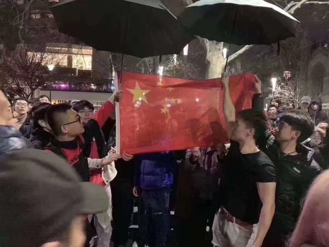 墨尔本中国留学生包围港独人士，齐唱国歌雨中为国旗撑伞。