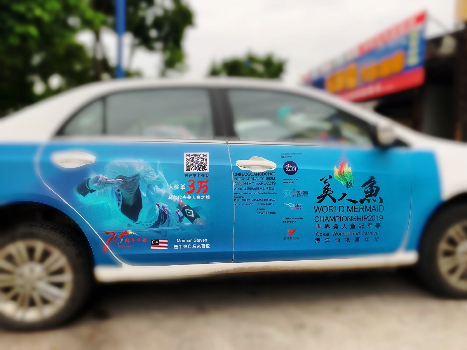 2019世界美人鱼冠军赛的宣传活动已盛大开展，广东省随处可见贴上海报的“滴滴”（电召车）。图为贴有陈虎巡照片的宣传车。