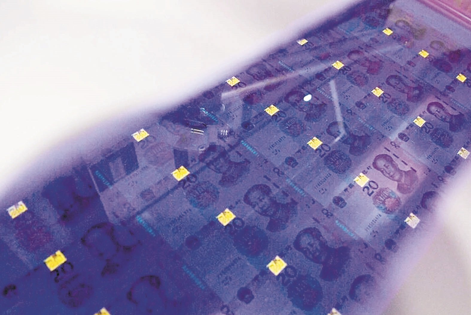 20元人民币新钞在紫外光下显现的萤光图案。面额数字颜色由金色变为绿色，并可见一条亮光带上下滚动。