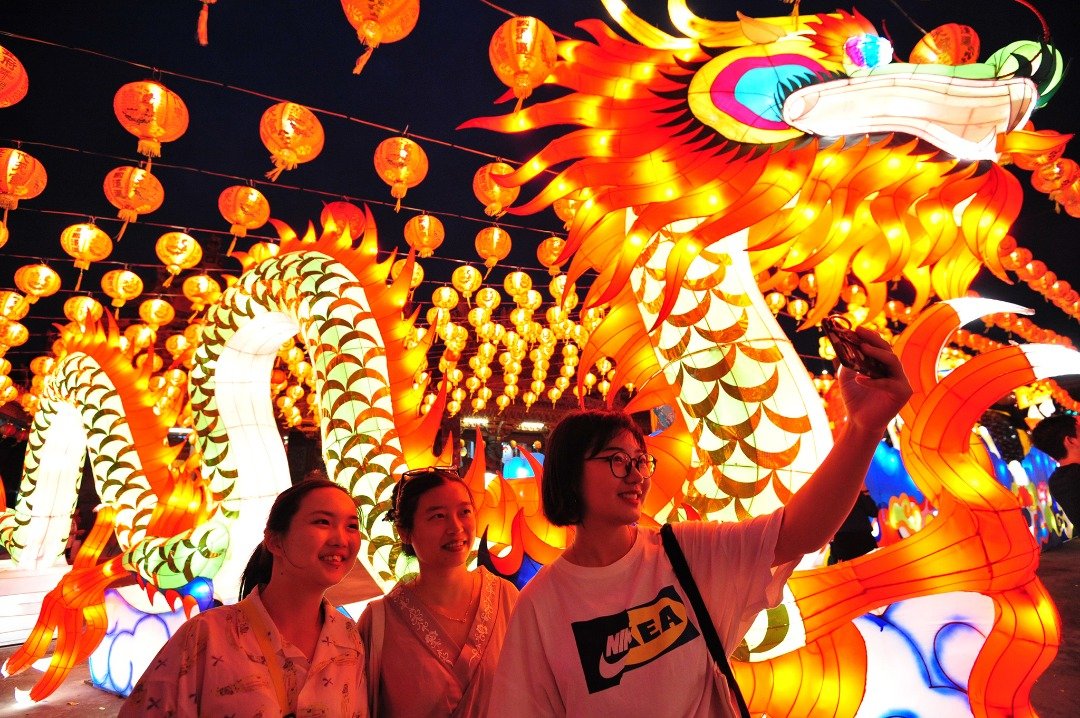 泰国曼谷郊区一座寺庙正举行这大型的灯会迎接新春佳节，吸引许多游客前来赏灯。这是游客们在灯会上，一条龙形灯笼前拍照留念。