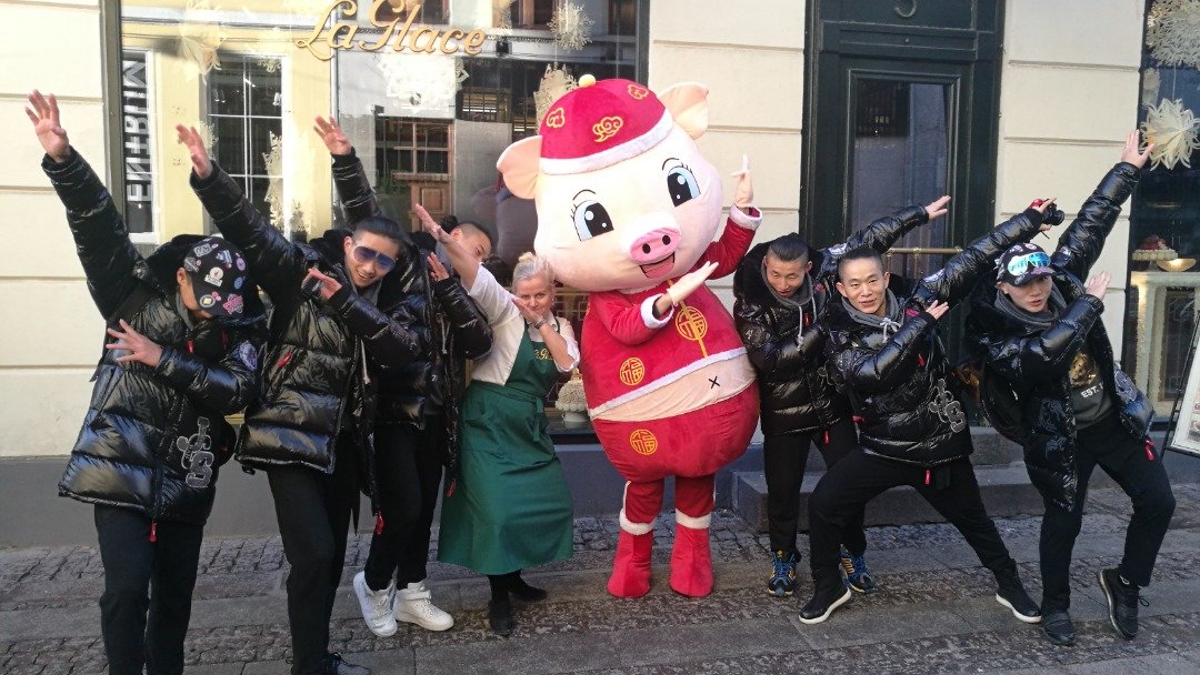 由丹麦哥本哈根中国文化中心与中国北京市文化和旅游部联合主办的“欢乐春节”系列活动之一“金猪闹新春”快闪表演在哥本哈根亮相。“金猪”吉祥物（中）与表演者在市中心甜品店门前摆弄造型。