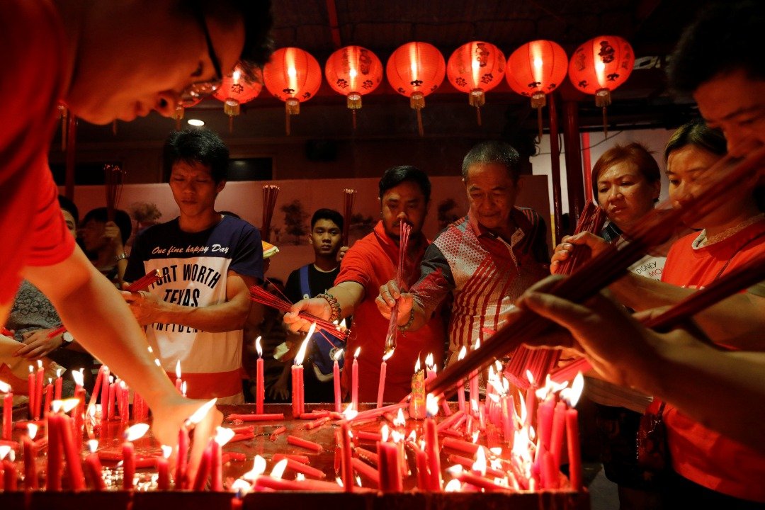 印尼华裔于除夕纷纷前往雅加达金德院上香，只见现场的民众借烛火点燃手中的香，再插进庙宇内的香炉，祈求平安。