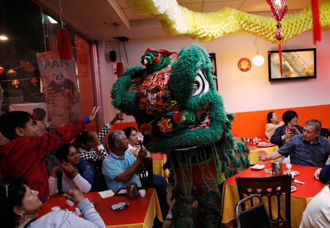 一只墨绿色鬃毛的醒狮上周三在墨西哥城、唐人街的一家华人餐厅中舞动，象征店铺以后将生意欣荣，在旁的顾客亦拿起手机拍照留念。