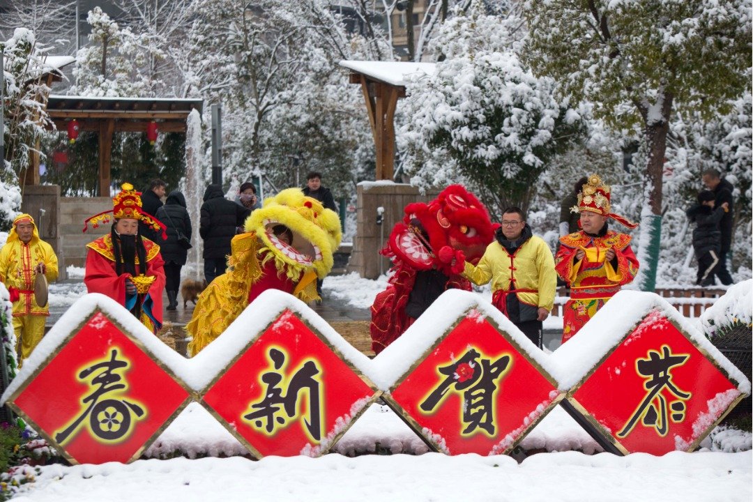 在中国东部江苏省泰州一个被白雪覆盖的风景区，多名作财神爷打扮的民间艺人在风雪中列队迎接游客的到来，一旁还有舞狮表演助兴。