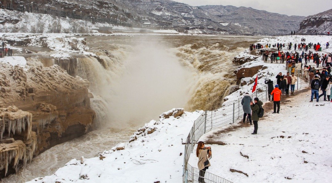 自上周六以来，中国山西省南部多个地区已迎来降雪。图为游客们站在白雪皑皑的黄河壶口瀑布上方，观望波澜壮阔的黄河流水。