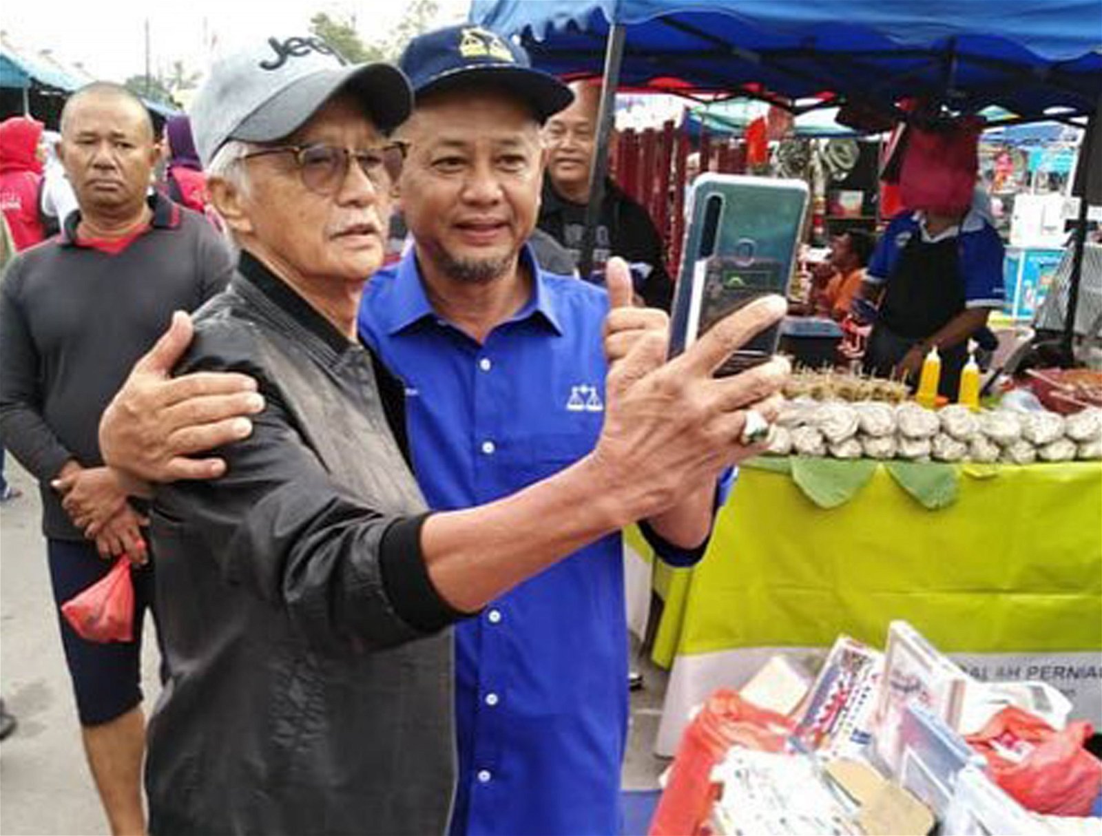 扎卡利亚哈纳菲（左2）走访峇玲珑巴刹时，受到不少选民的 支持，有者更举起手机来张自拍合影。