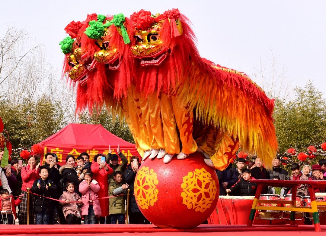 中国河南省开封翰园在文化庙会展开了舞狮表演。这是3头身披金、黄、红毛发的北狮，一齐站在红色圆球缓缓地向前移动，吸引不少游客驻足围观，有的还拿起手机拍照留念。