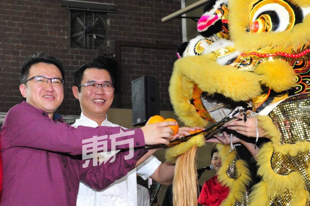 刘镇东（左）和陈泓宾（右）接领舞狮赠送的祝福年柑，象征新的一年大吉大利。（摄影：杨金森）