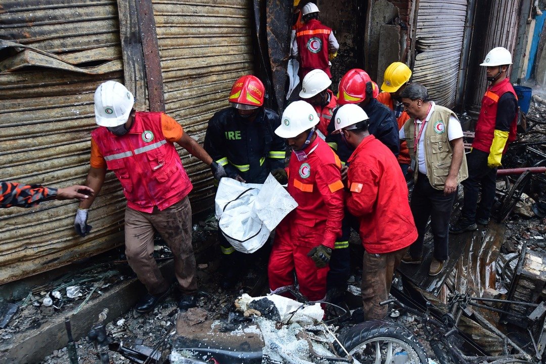 救援人员从失火的建筑内，抬出一名遇难者的遗体。该建筑是一栋公寓，但也用作存放化学物品的仓库。