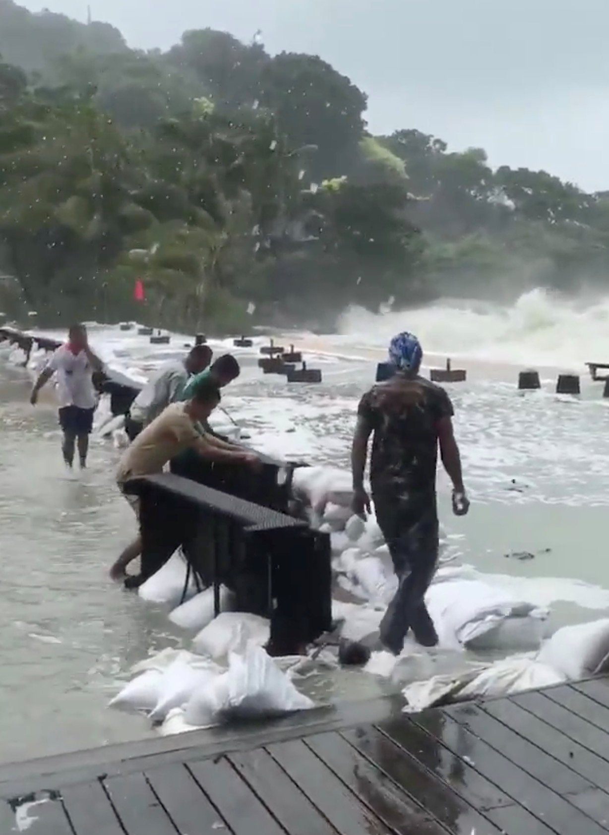 泰国民众在苏梅岛通塞海滩，利用一袋袋的沙包及桌子，在岸边筑起 一道防浪墙。一旁可见层层卷起的大浪，不断地向海滩扑去，场面骇人。 （推特／路透社）