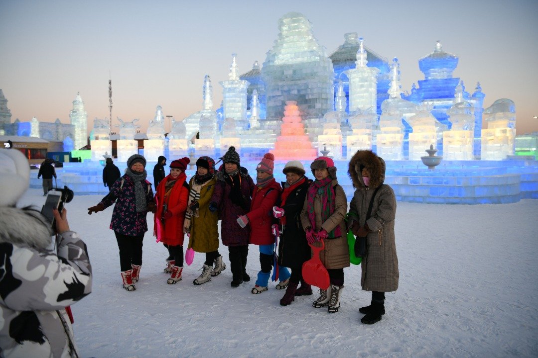 此次的冰雪节推出了冰雪旅游、文化、时尚、经贸及体育等方面的近百项活动，将吸引不少游客前去参观。这是游客们在一座冰雕建筑前，拍团体照留念。
