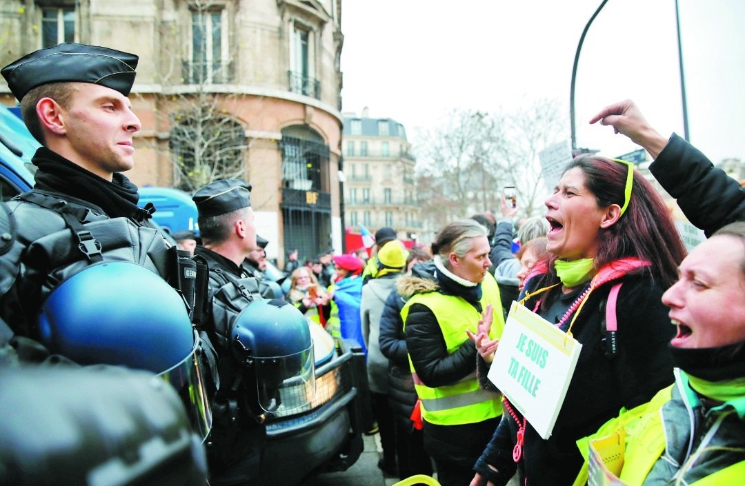 周日参与游行的“黄背心妇女”胸口悬挂“我是你的女儿”或“我是你的祖母”口号牌，向驻守在巴黎街头的镇暴警察高喊口号。