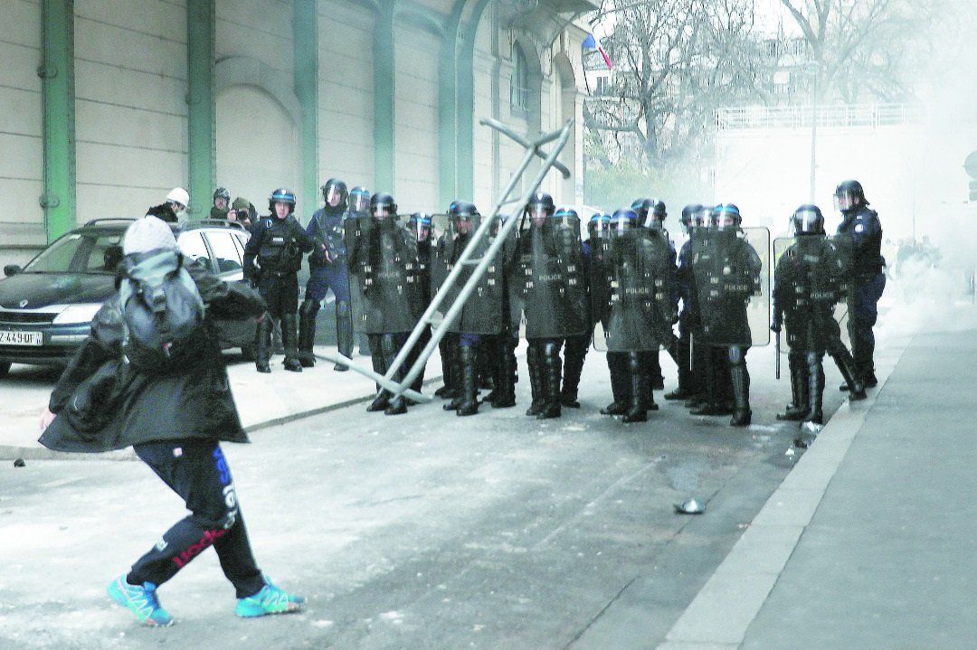 在进入今年首个周末，法国黄背心运动示威者周六 再在巴黎街头上演全武行，一名示威者将一个栏栅 丢向警方，镇暴警察则以催泪弹回应。